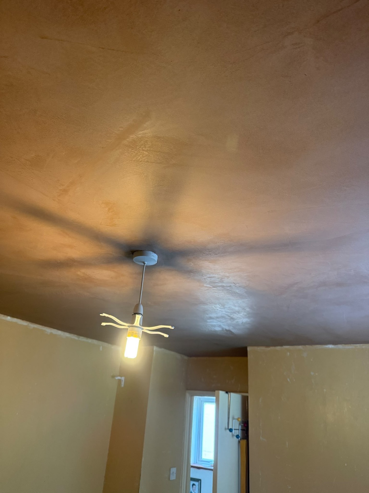 Newly plastered ceiling lit by a pendant light