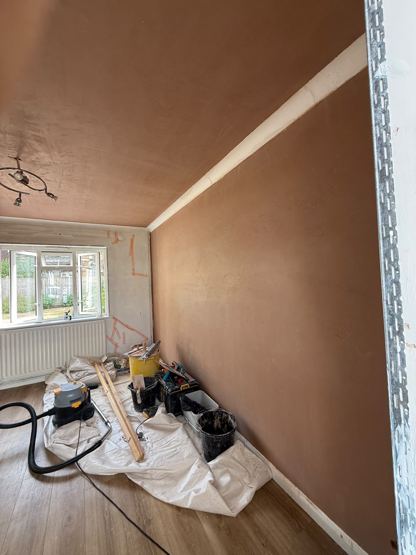Smooth new skim coat across a full-height wall and ceiling